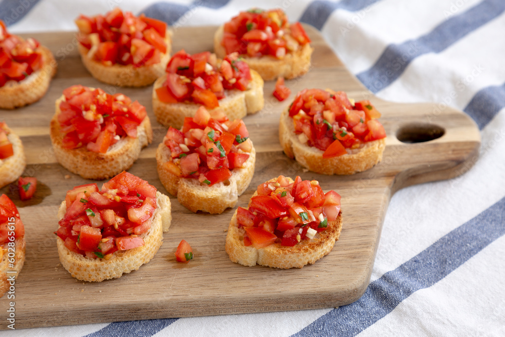 Homemade Italian Bruschetta Appetizer with Fresh Basil and Juicy Tomatoes on a Wooden Board, side view. Homemade Italian Bruschetta Appetizer with Fresh Basil and Juicy Tomatoes on a Wooden Board, side view.