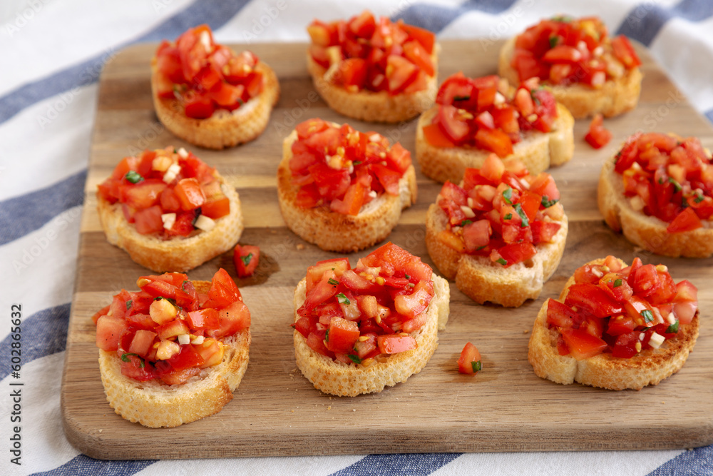 Homemade Italian Bruschetta Appetizer with Fresh Basil and Juicy Tomatoes on a Wooden Board, side view. Homemade Italian Bruschetta Appetizer with Fresh Basil and Juicy Tomatoes on a Wooden Board, side view.