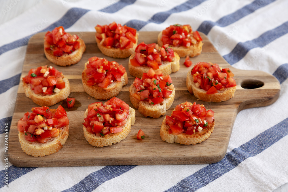 Homemade Italian Bruschetta Appetizer with Fresh Basil and Juicy Tomatoes on a Wooden Board, side view. Homemade Italian Bruschetta Appetizer with Fresh Basil and Juicy Tomatoes on a Wooden Board, side view.