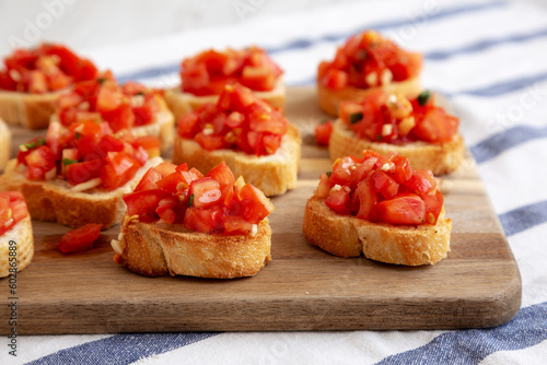 Homemade Italian Bruschetta Appetizer with Fresh Basil and Juicy Tomatoes on a Wooden Board, side view. Close-up.