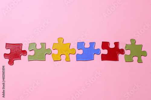 Multicolored pieces of puzzles isolated on pink background. Concept of autistic disorder. Autism awareness, Autism spectrum disorder family support concept. 
