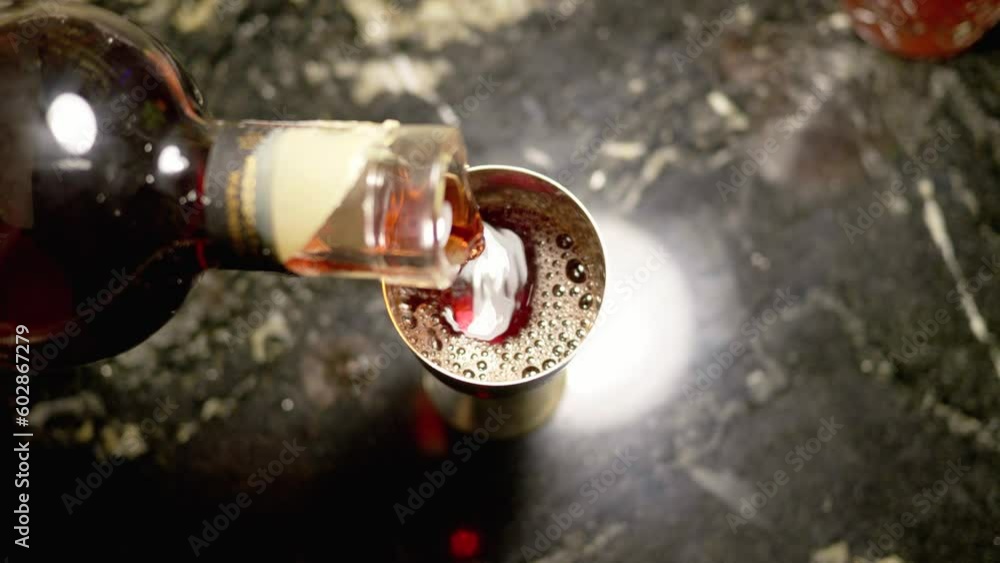 The bartender pours alcohol from a glass bottle into a glass The bartender pours alcohol from a glass bottle into a glass