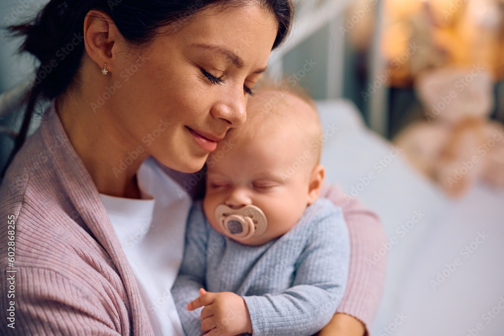 Young caring mother holds her sleeping baby at home. Young caring mother holds her sleeping baby at home.