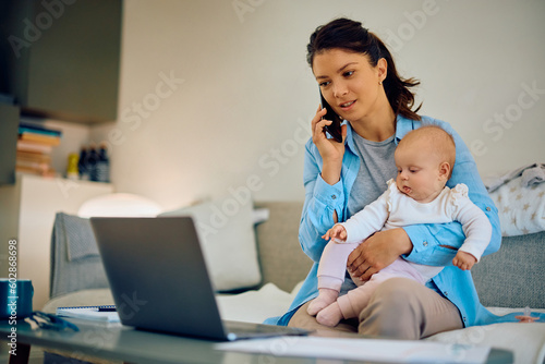 Busy mother talks on cell phone while babysitting her daughter and working at home.