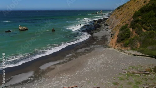 Aerial cinematic drone California coastline Highway 1 Montana Pacifica Gray Whale Cove State Beach Big Sur black sand aqua deep blue water windy surf epic roadtrip forward pan up reveal movement photo