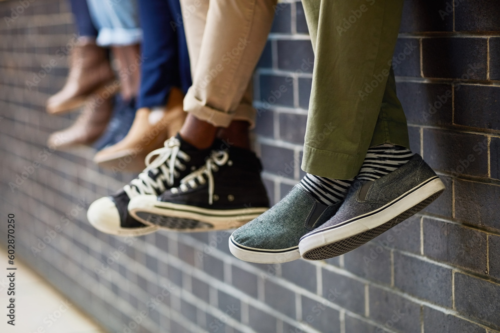 Brick wall, students feet and friends outdoor on university campus together with sneakers. Relax, youth and foot at college with people legs ready for education, study and urban shoes while sitting Brick wall, students feet and friends outdoor on university campus together with sneakers. Relax, youth and foot at college with people legs ready for education, study and urban shoes while sitting