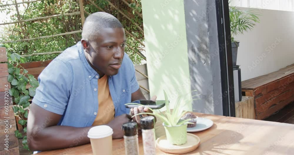 Happy african american man talking on smartphone at coffee shop, slow motion Happy african american man talking on smartphone at coffee shop, slow motion