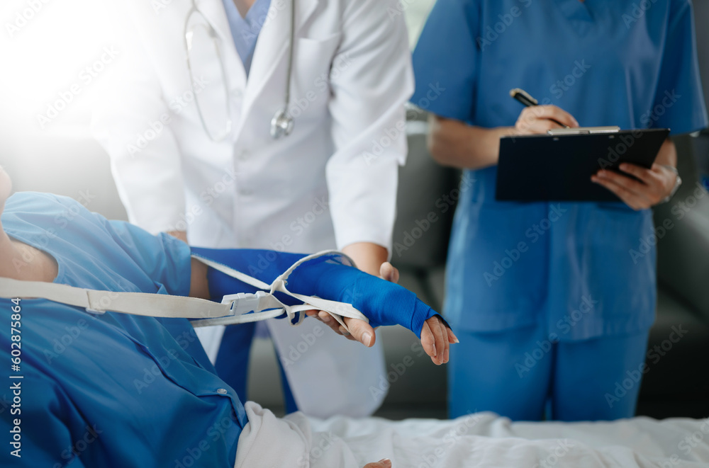 Two doctors talking to a patient lying in his bed with receiving saline solution in hospital . Two doctors talking to a patient lying in his bed with receiving saline solution in hospital .