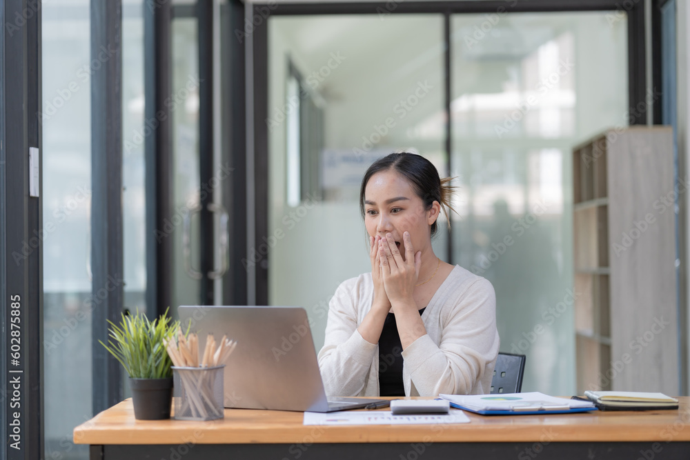 A surprised woman looking at a laptop screen, sitting at a work desk, reading good unexpected news in an email, or message, excited by a money refund, job promotion, or great sale offer A surprised woman looking at a laptop screen, sitting at a work desk, reading good unexpected news in an email, or message, excited by a money refund, job promotion, or great sale offer