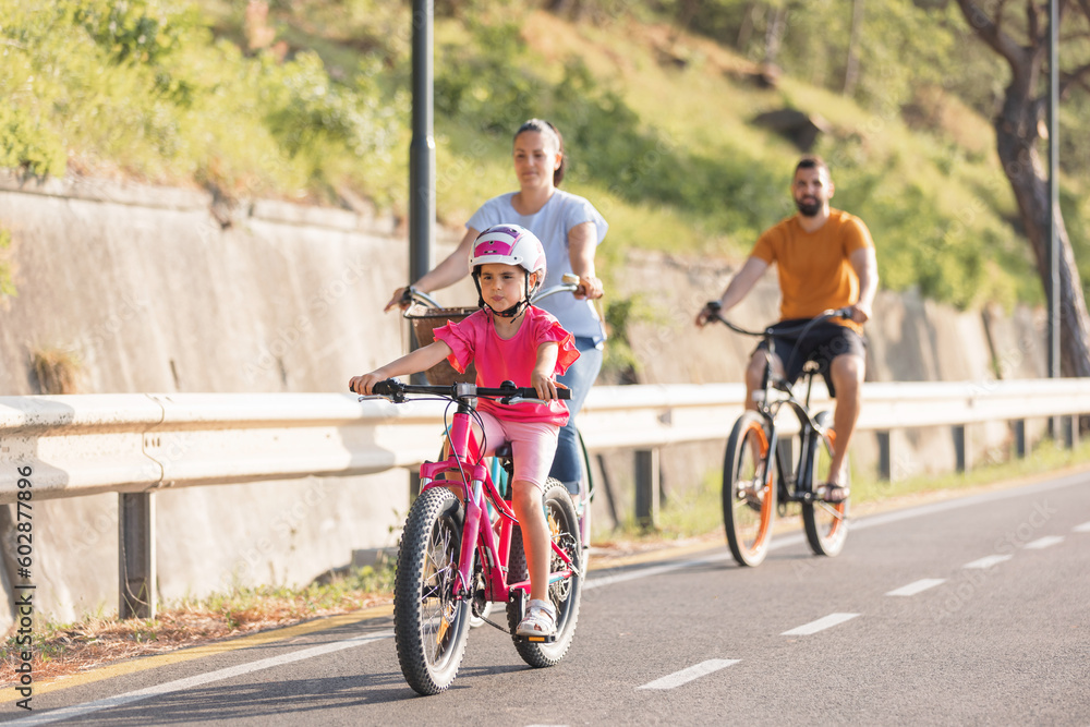 Mother, father and girl child having fun on vacation cycling near the sea. Family coastal bike ride.