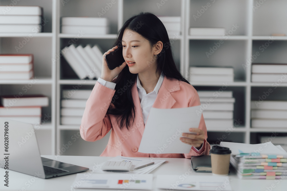 Cheerful young businesswoman holding smartphone while working in her office room. Cheerful young businesswoman holding smartphone while working in her office room.