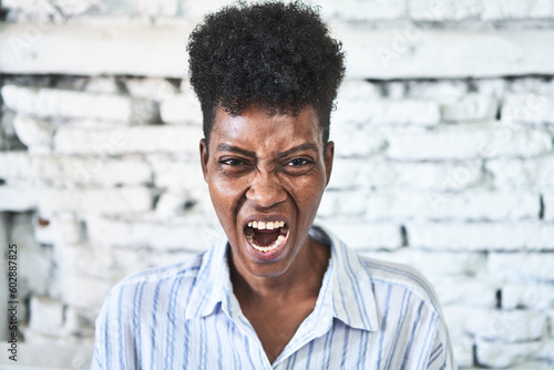 Foto A miggle-aged african woman sitting on her sofa screaming very angry and aggressive