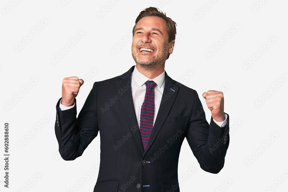 A middle-aged businessman isolated raising fist after a victory, winner concept. A middle-aged businessman isolated raising fist after a victory, winner concept.
