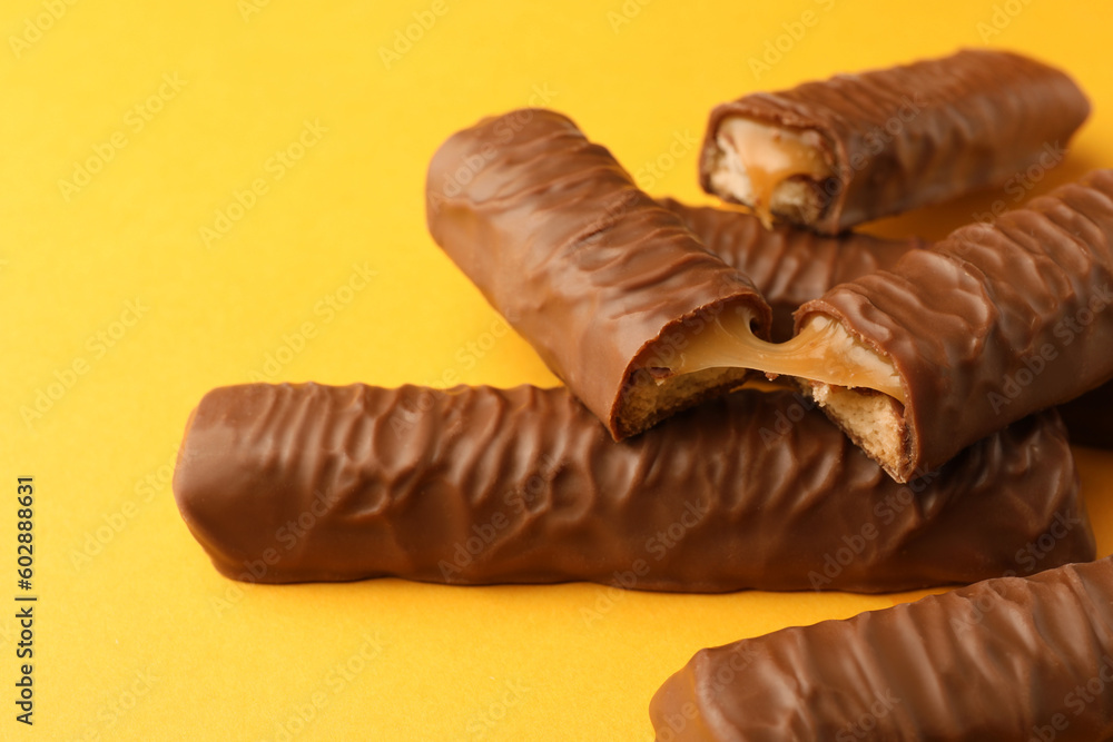 Sweet tasty chocolate bars with caramel on yellow background, closeup Sweet tasty chocolate bars with caramel on yellow background, closeup