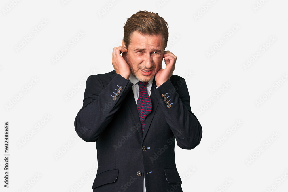 A middle-aged businessman isolated covering ears with hands. A middle-aged businessman isolated covering ears with hands.