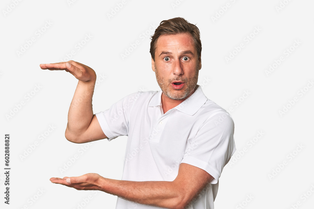A middle-aged man isolated shocked and amazed holding a copy space between hands. A middle-aged man isolated shocked and amazed holding a copy space between hands.
