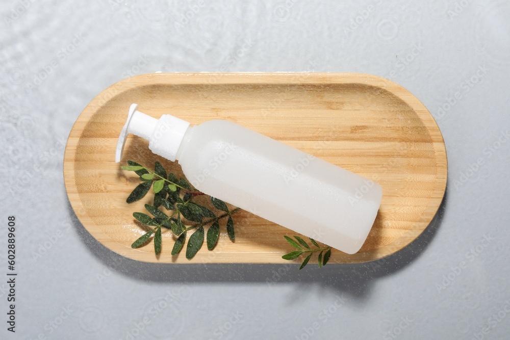 Wooden tray with bottle of facial cleanser and leaves on light grey background, top view Wooden tray with bottle of facial cleanser and leaves on light grey background, top view