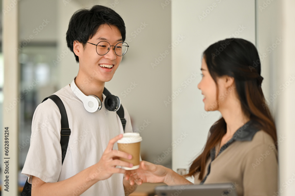 Smiling young college friends talking while standing at lockers in campus. Youth lifestyle concept Smiling young college friends talking while standing at lockers in campus. Youth lifestyle concept