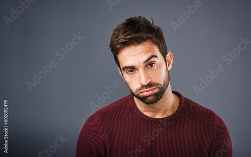 Bored, portrait and annoyed man in studio unhappy and moody against a grey background space. Sad face of depression and man with negative attitude posing with isolated, whatever or tired expression photo