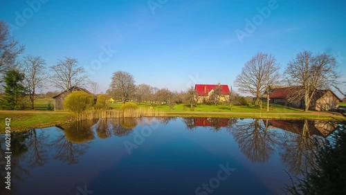 Timelapse shot of fog passing over rural cottages throughout the day with a pond in the foreground. photo