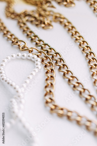A necklace of white beads with chains of jewelry on a white aesthetic background.