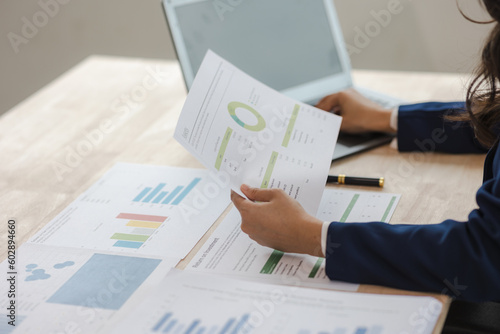 Close-up of asian businesswoman using calculator and laptop for mathematical finance on wooden table, tax, accounting, statistics and analytical research concept