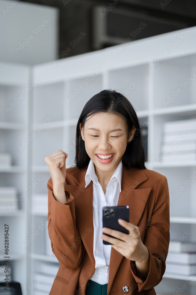 Happy Asian woman holding a smartphone, happy smiling, getting bonus money. Happy Asian woman holding a smartphone, happy smiling, getting bonus money.