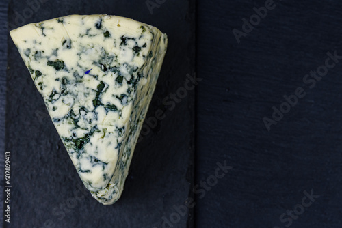 Piece of the blue cheese with mold on slate board. Top view