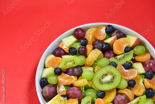 Healthy fresh fruit salad bowl on red background. Top view. Healthy food concept  healthy high vitamin fruit  mixed fruit background.