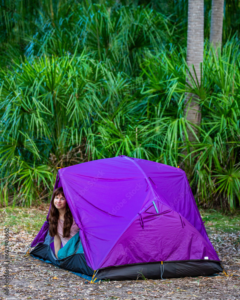 A beautiful girl enjoys a morning in the bush looking out of her purple tent. Camping in Australia. Wreck Rock campground, Deepwater National Park, Queensland, Australia
