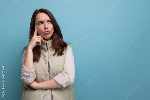 a young brunette woman in a shirt and a vest in an incomprehensible state is upset against the background with copy space