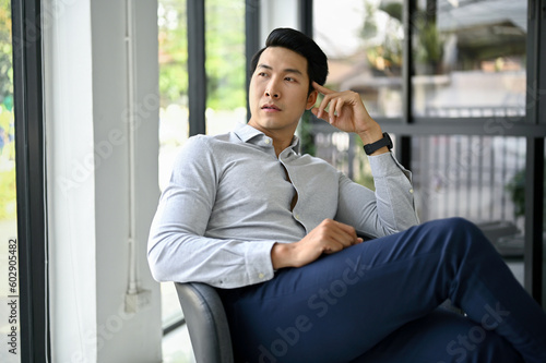 Portrait, Thoughtful Asian businessman or male CEO sits in an office lounge.