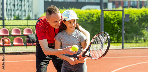 Father is a tennis coach for his daughter. Female child is playing in tandem with her daddy in doubles tennis