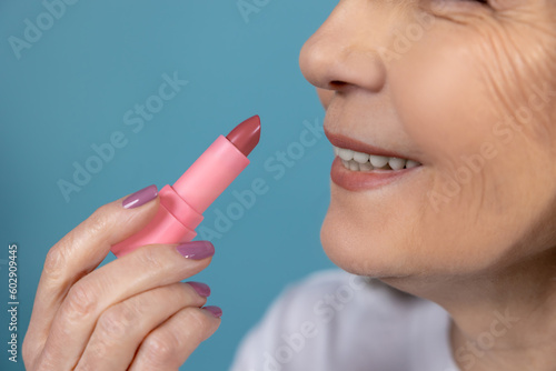 Beautiful aging woman with lipstick doing makeup photo