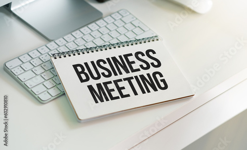 Business Meeting text on a notebook with chart, keyboard on white table.