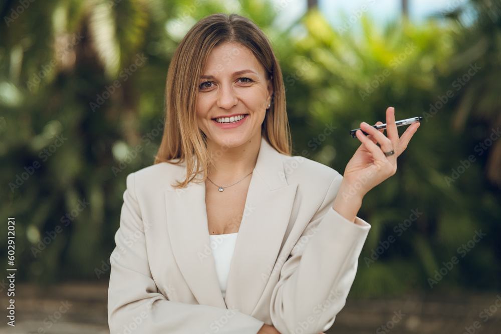 Confident businesswoman with pen smiling at camera in park Confident businesswoman with pen smiling at camera in park