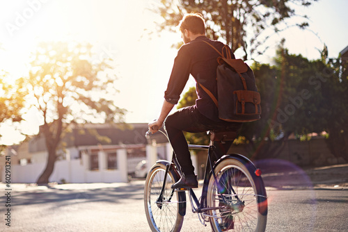 Travel, bicycle and back of man in road with lens flare for exercise, commute and cycling in morning. Transport, city and male cyclist on bike for eco friendly traveling, carbon footprint and journey