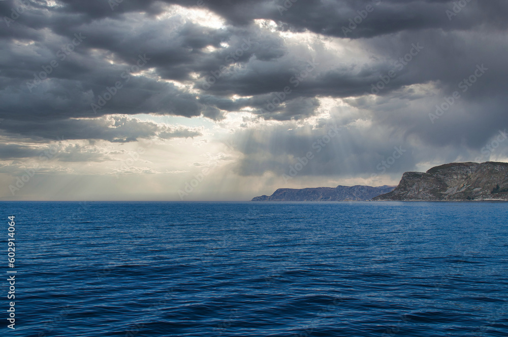 View from the sea to the West Cape in Norway in sunshine with heavy clouds.