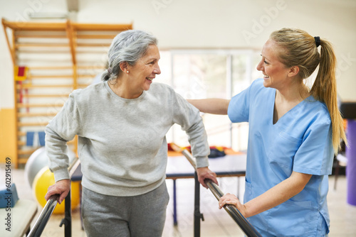 Physiotherapist assisting elderly woman in movement therapy at rehab center photo