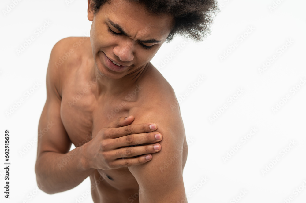 Curly-haired young guy suffering from pain in his shoulder