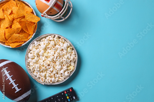 Top view of snacks for watching a football game over blue background with copy space. Super bowl concept.