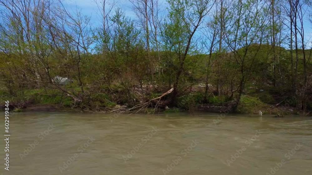 Batumi, Georgia – April 9, 2023: Muddy Chorochi river because of spring snow melting high in mountains. Muddy river drone moving downstream at the current speed facing right river bank Batumi, Georgia – April 9, 2023: Muddy Chorochi river because of spring snow melting high in mountains. Muddy river drone moving downstream at the current speed facing right river bank