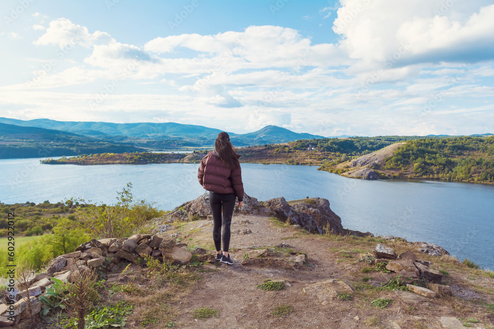 Obraz premium Traveler woman walking above a blue lake with stunning panoramic view .Traveling in the nature in Bulgaria . Pchelina Lake