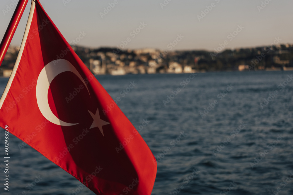 A red flag with a white star on itTurkey flag and Istanbul view. Boat view of the national flag of Turkey and the coastline of Istanbul during the Bosphorus cruise.