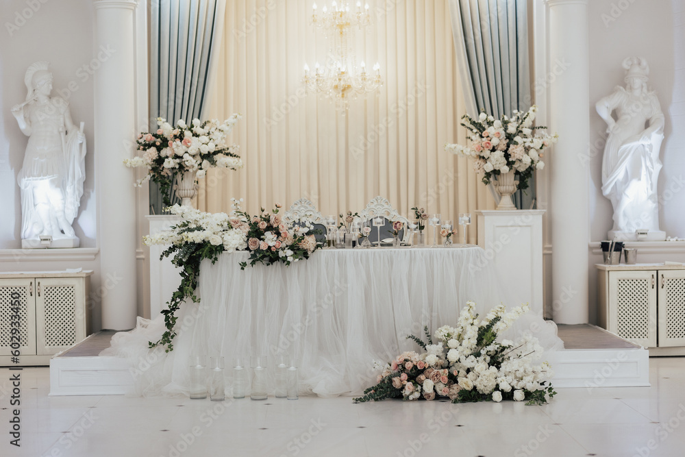 Luxury elegant classic table for the bride and groom decorated with flowers and vases with candles.