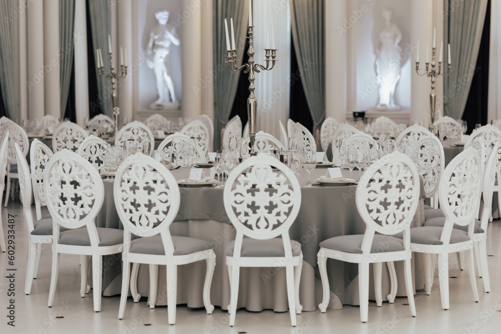 A white table with chairs in a restaurant with a statue in the background.