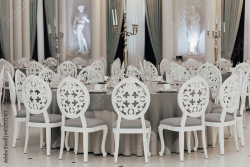 Obraz na płótnie A white table with chairs in a restaurant with a statue in the background. w salonie