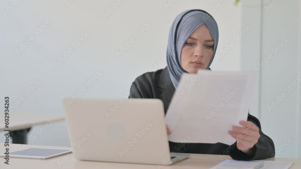 Reading Document by Arab Businesswoman and Working on Laptop Reading Document by Arab Businesswoman and Working on Laptop