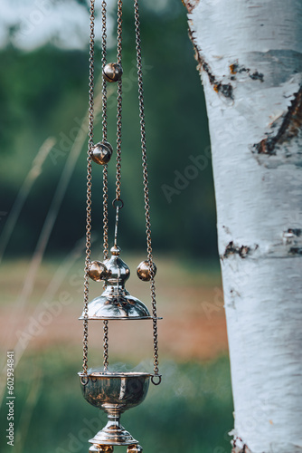 church censer with smoke of incense on a background of nature next to a birch