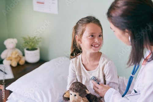 Fototapeta Naklejka Na Ścianę i Meble -  Medical, children and a girl at the pediatrician for an appointment or checkup in the hospital. Healthcare, stethoscope and cardiology with an adorable female child sitting on a bed in the clinic